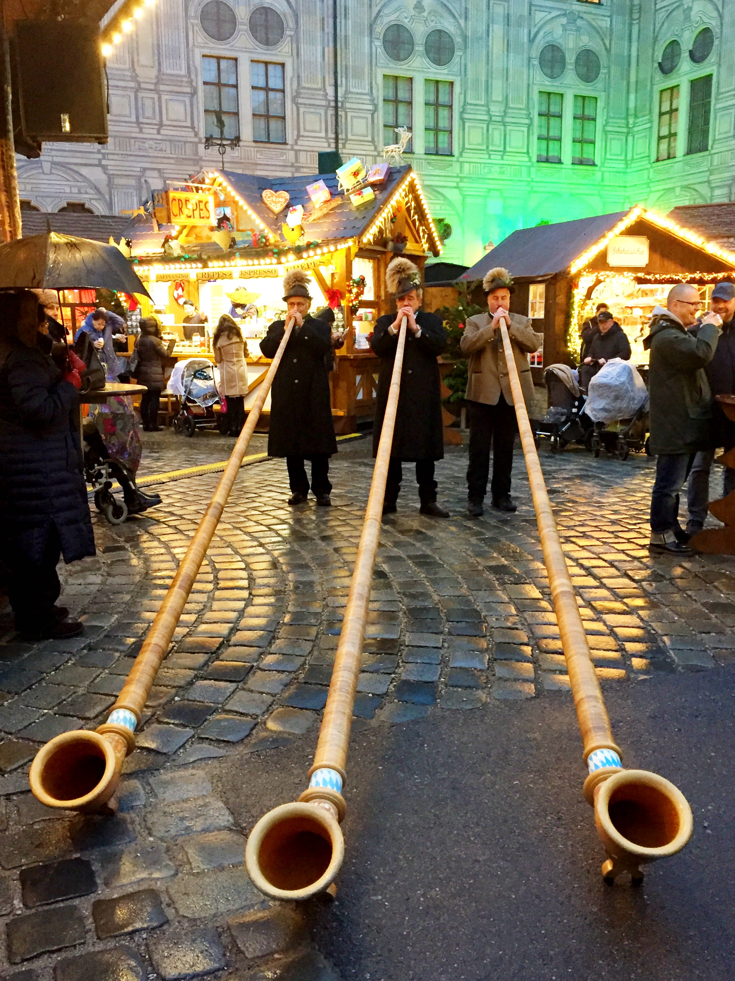 3 men playing long wooden horn instruments at a Christmas Market