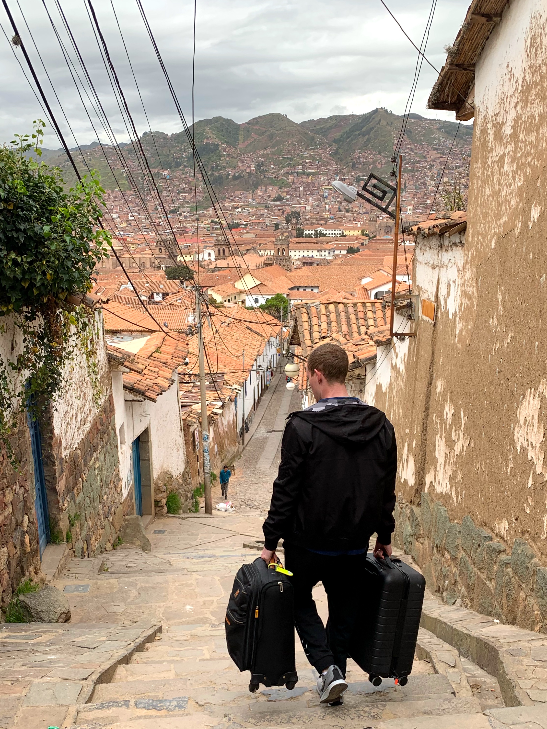 Mark carrying suitcases down the stairs of the San Blas neighborhood in Cusco, Peru